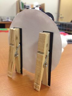 a pair of wooden clothes pegs on top of a white plate with black handles