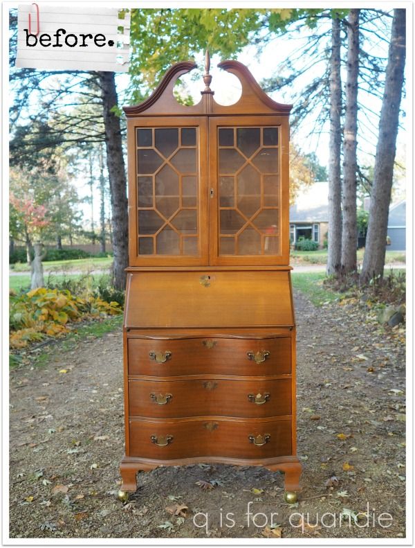 an old wooden desk with glass doors and drawers in the middle of a forest area