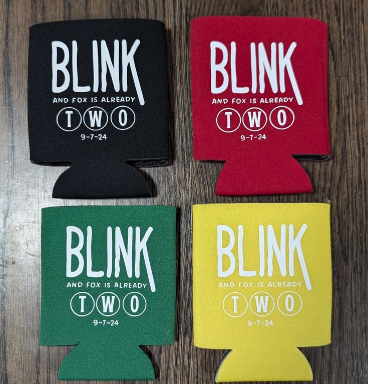 four can coolers with the words blink two and two are on a wooden table