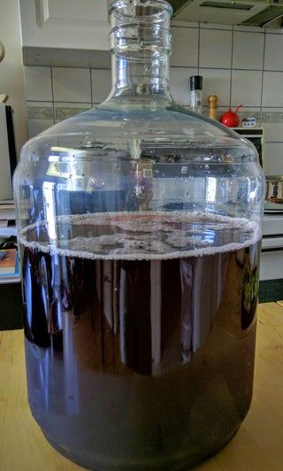 a large glass bottle filled with liquid on top of a wooden table