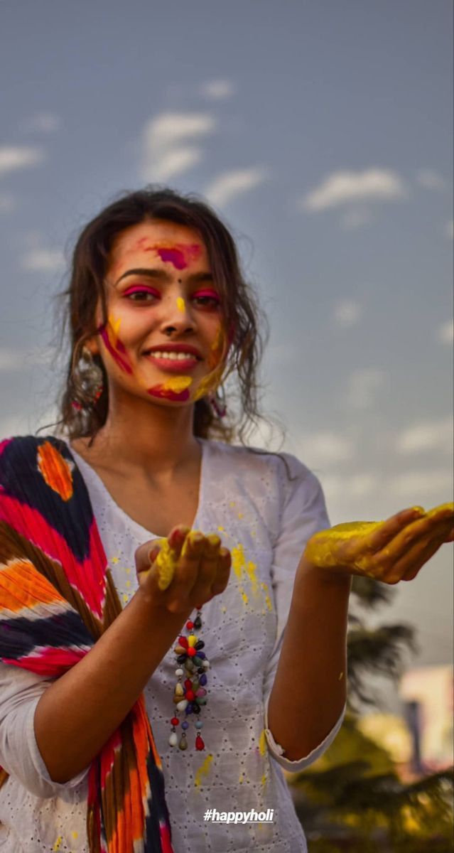 a woman with her face painted in yellow and red is holding something up to the camera