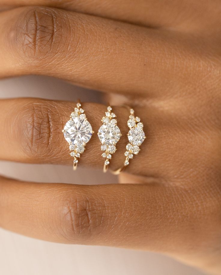 a woman's hand with three different rings on her fingers and one has an engagement ring