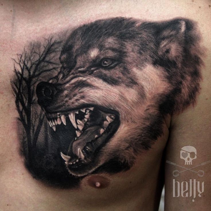 a man's chest with a wolf and tree tattoo on his chest is shown