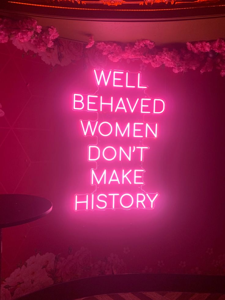 a pink neon sign that says well behaved women don't make history