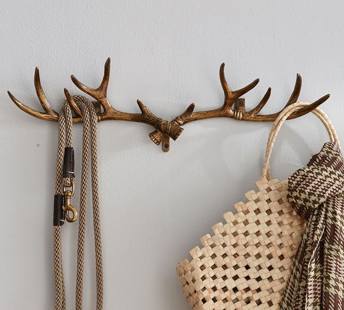 a deer antlers head mounted to the side of a wall next to a woven bag