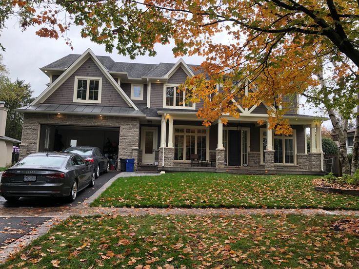 a car parked in front of a house with autumn leaves on the grass and trees