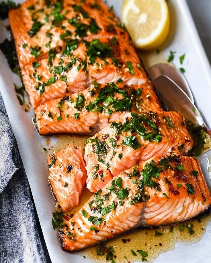 two salmon fillets on a plate with lemons and parsley