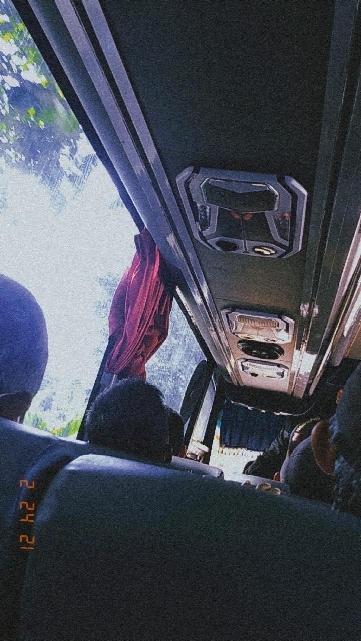 the inside of a bus with people sitting on seats and trees in the back ground