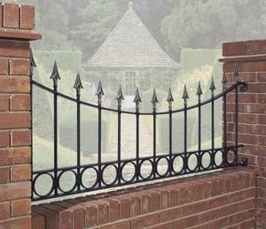 a brick wall with a black iron fence on it and mountains in the back ground