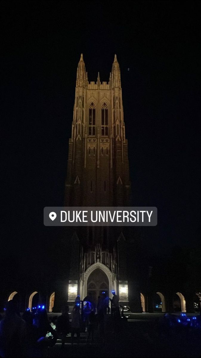 the duke university sign is lit up at night with people standing in front of it