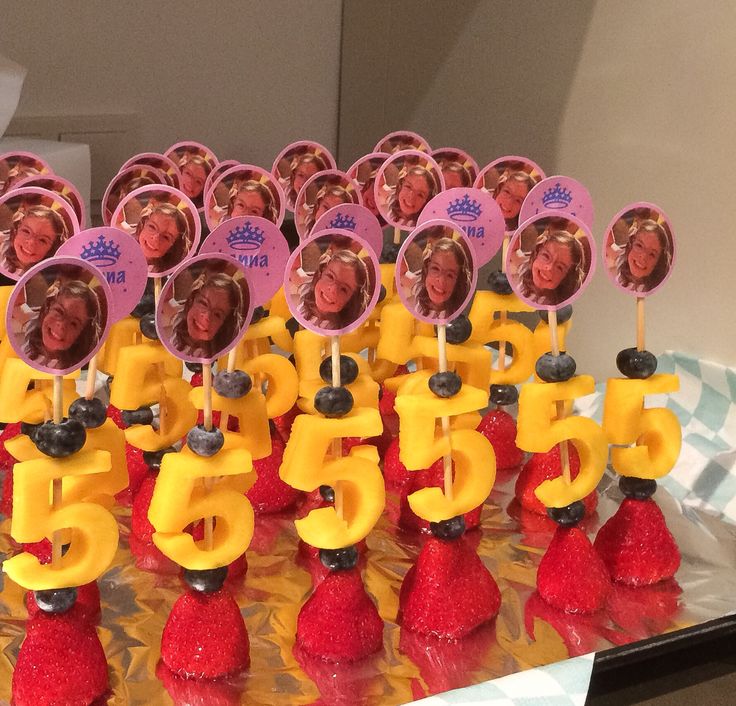 a table topped with lots of red strawberries and cake toppers covered in photos