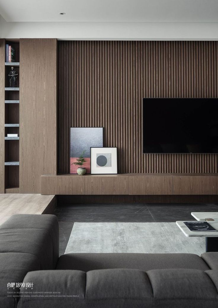 a modern living room with wood paneling and gray couches in front of a flat screen tv