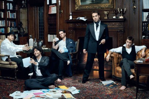 a group of men in suits and ties sitting on the floor next to each other