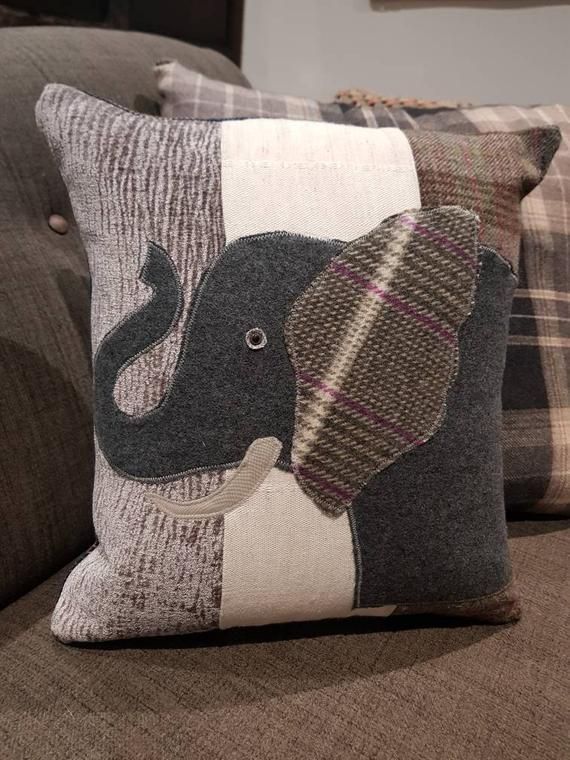 two pillows with an elephant on them sitting on a couch