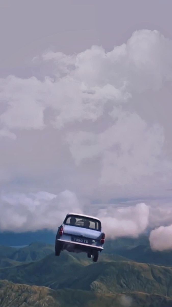 a car is flying through the air with mountains and clouds in the backgroud