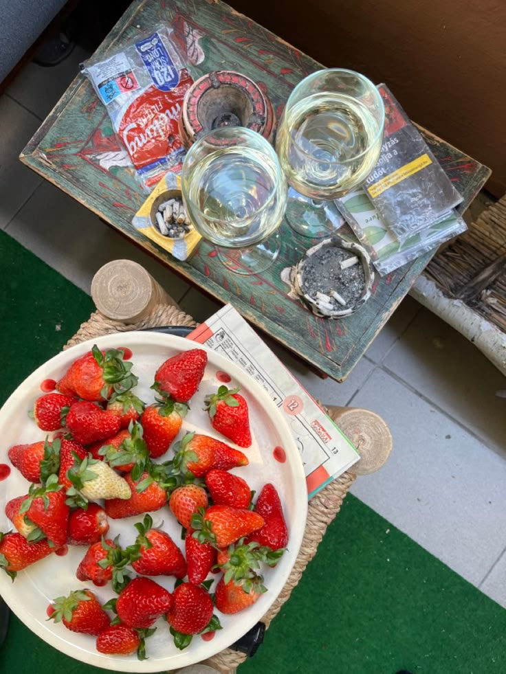 strawberries are on a plate next to empty wine glasses