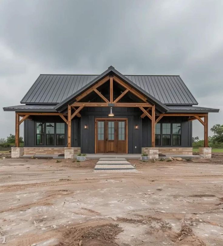 a black and brown house sitting on top of a dirt field