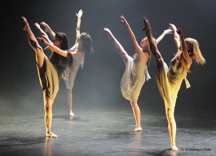 three ballet dancers in yellow and white outfits on stage with their arms raised up to the side