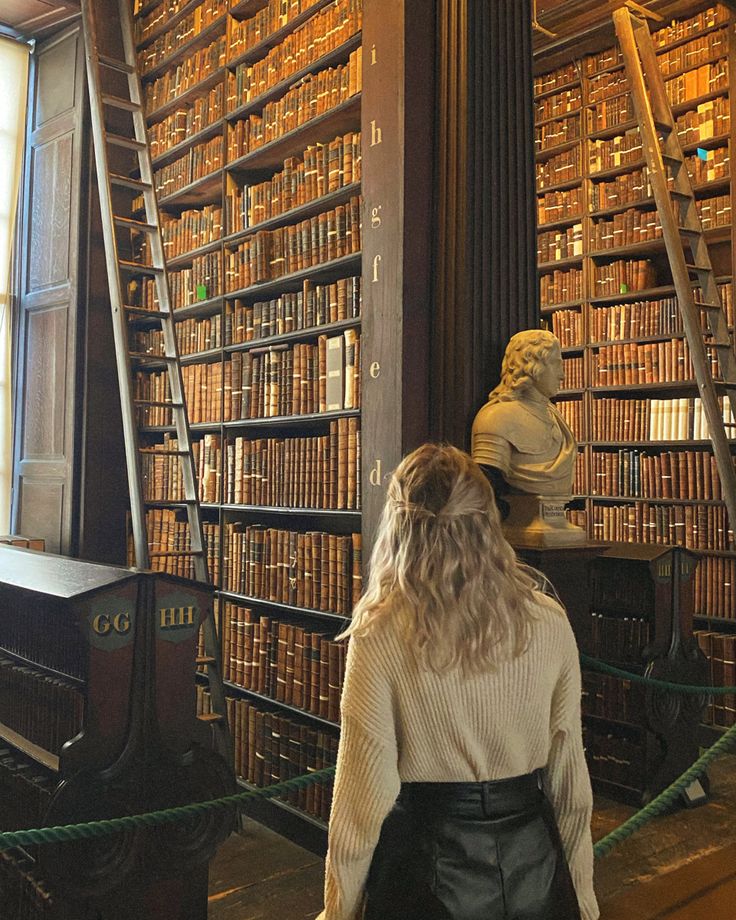 a woman standing in front of a bookshelf filled with lots of book shelves