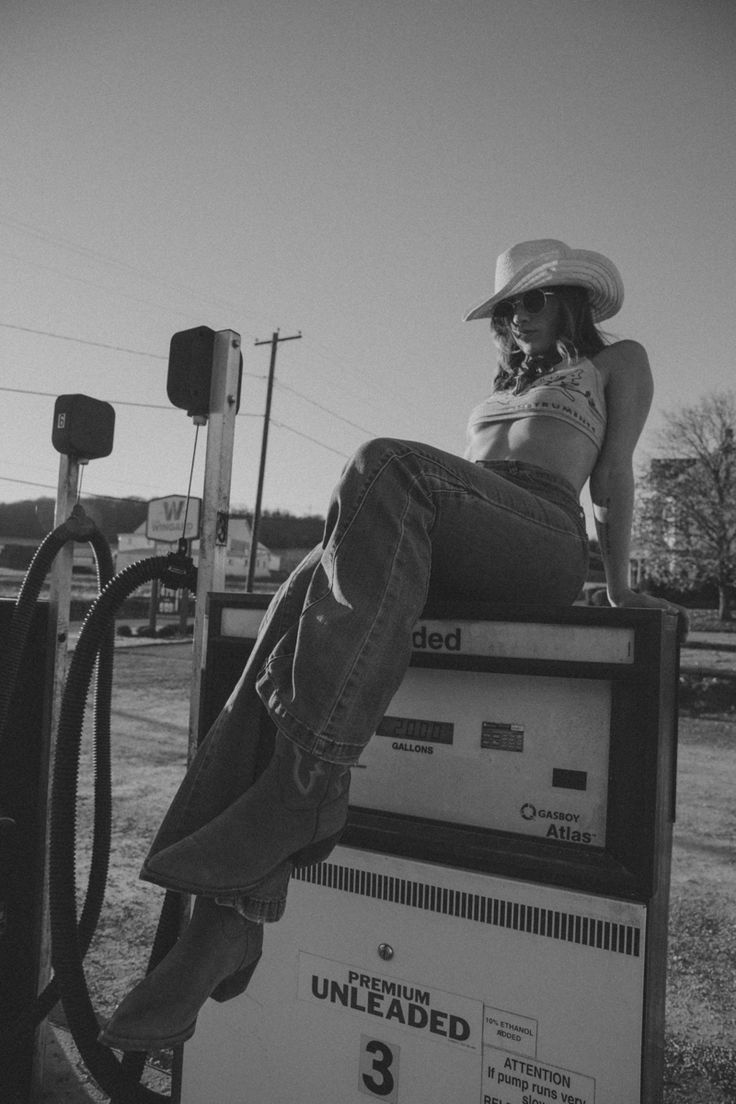 a woman sitting on top of a gas pump