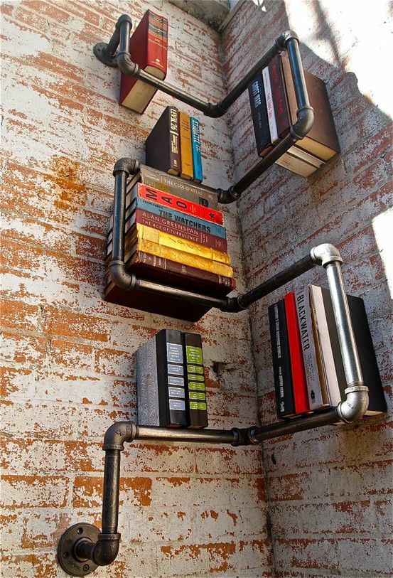 some books are sitting on the wall with metal pipes