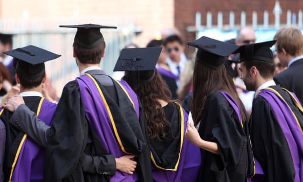 a group of people in graduation gowns and caps standing together with their arms around each other