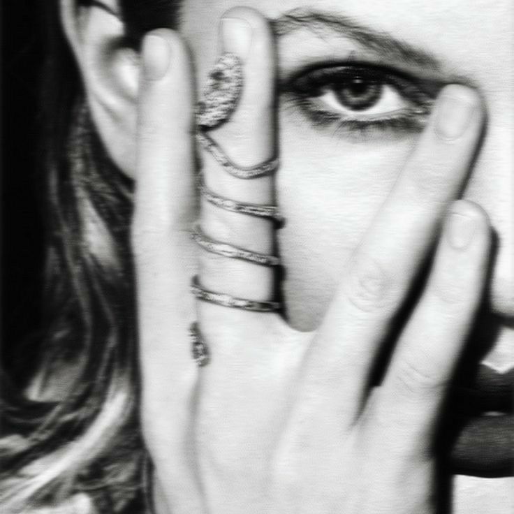 a black and white photo of a woman holding her hands to her face with rings around her eyes