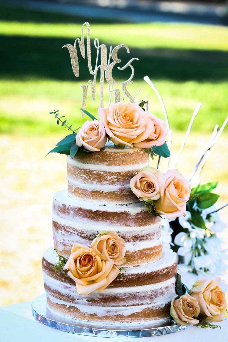 a three tiered cake with flowers on top and the word mr and mrs spelled in cursive