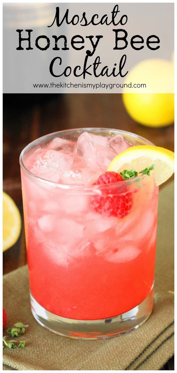 a close up of a drink in a glass with ice and raspberries on the rim