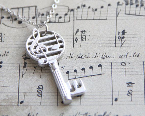 a silver key necklace with musical notes on the sheet music is in the foreground