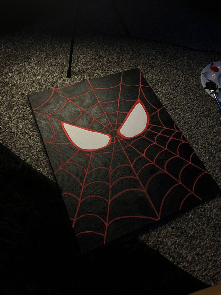 a spider - man face is on the floor in front of a black carpeted area