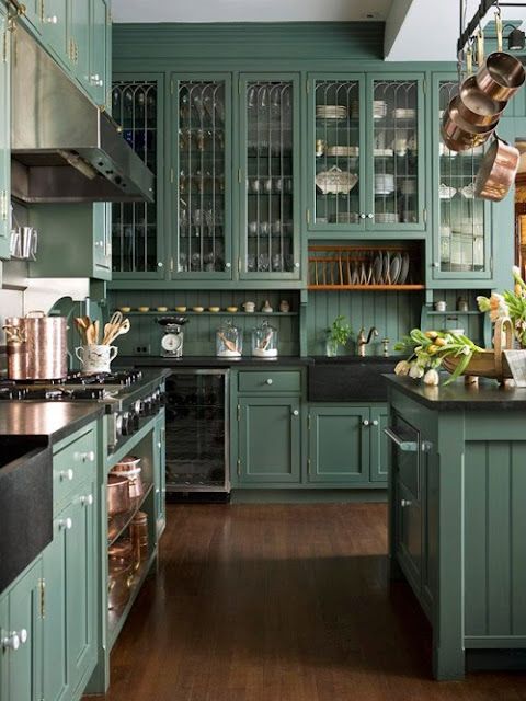 a kitchen with green cabinets and wooden floors