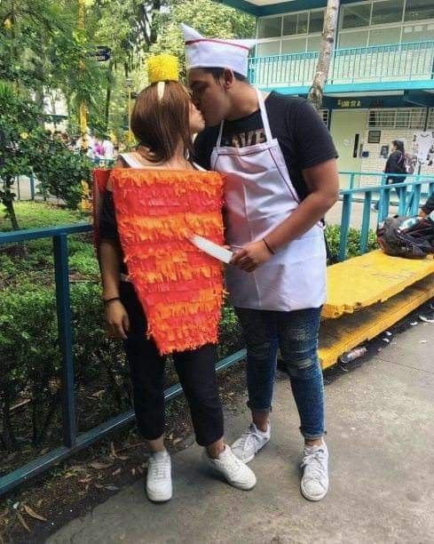 a man and woman dressed up as chefs kissing on the cheek while standing in front of a fence