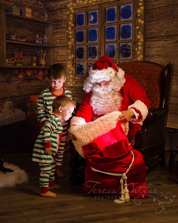 a little boy standing next to santa clause