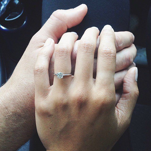 two hands holding each other while sitting in a car