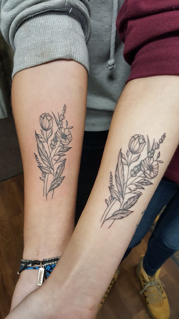 two people with matching tattoos on their arms, one has a flower and the other has a leaf