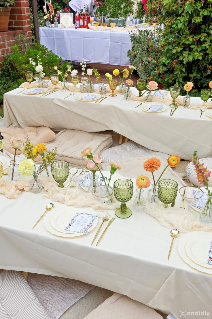 the table is set up with flowers and plates for an outdoor dinner party or celebration