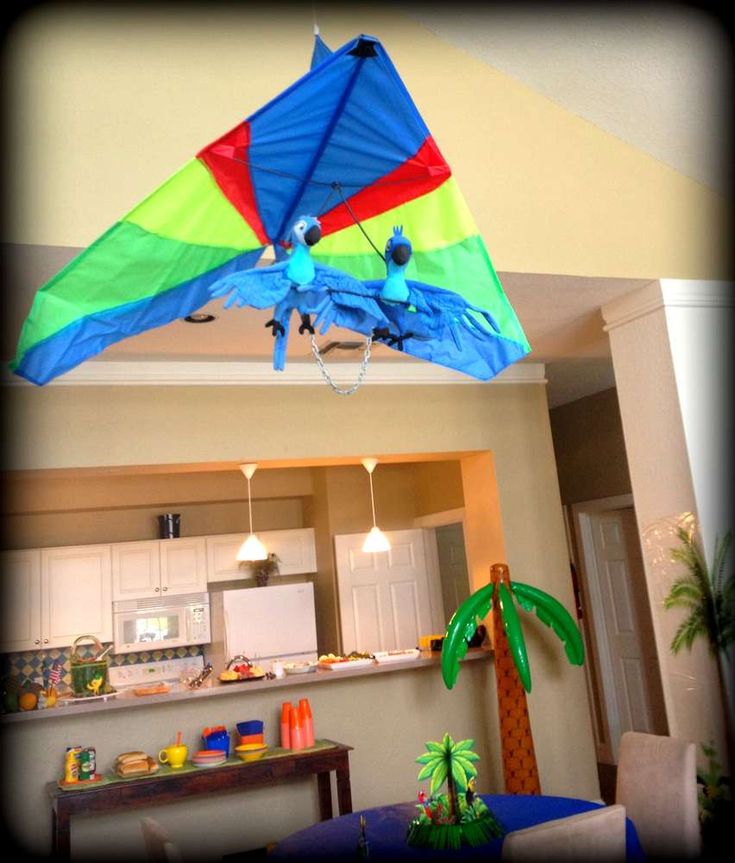 a colorful kite is flying in the air above a living room and kitchen counter area