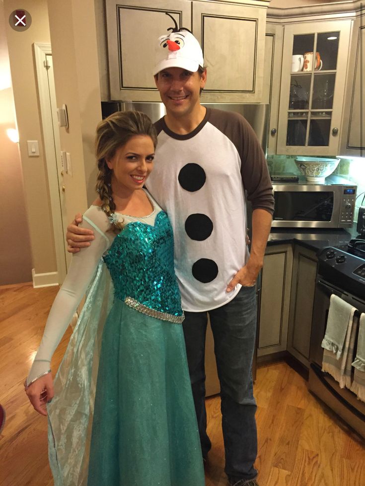 a man and woman dressed up as frozen princesses in the kitchen with their arms around each other