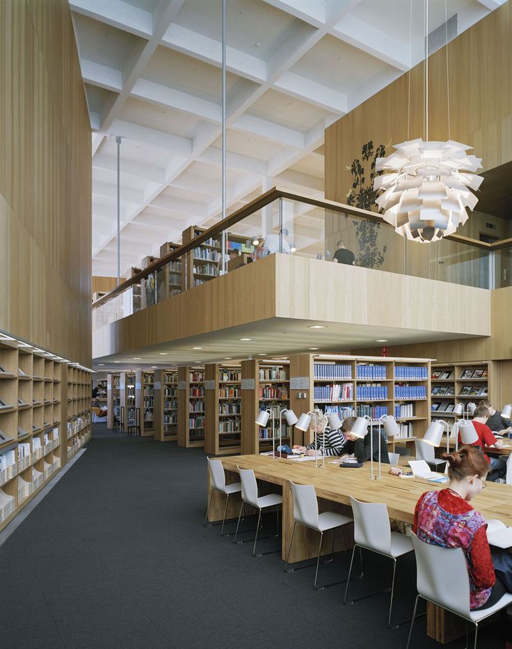 people are sitting at long tables in the library