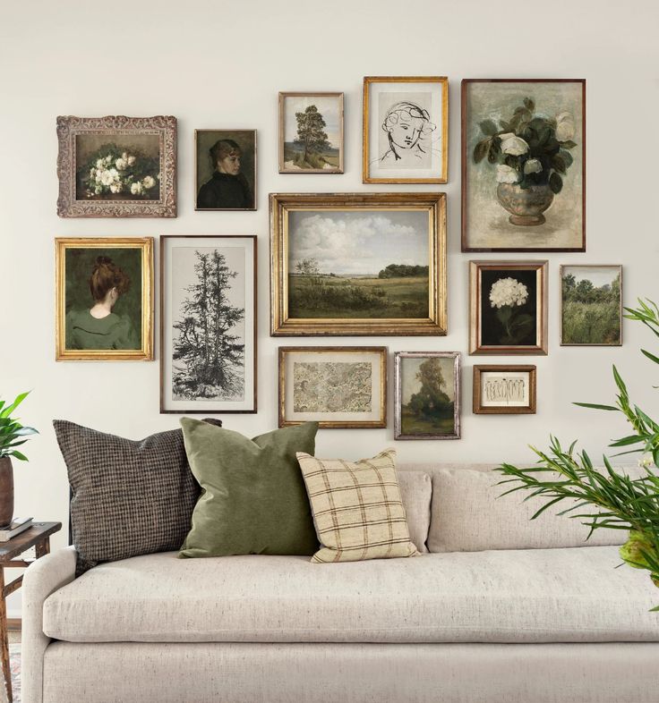 a living room filled with lots of framed pictures on the wall next to a couch