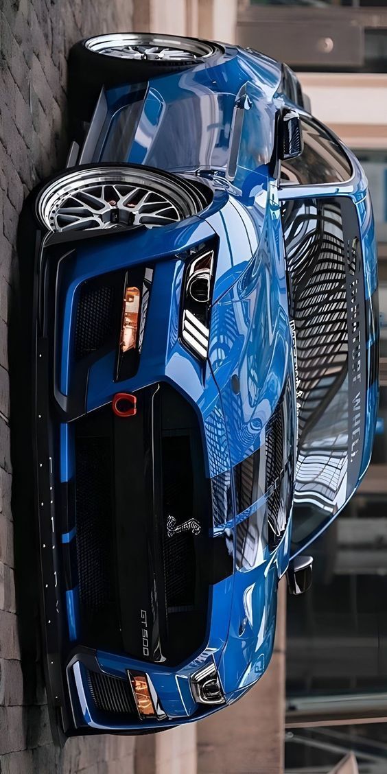 a blue sports car parked on the side of a brick wall next to a building