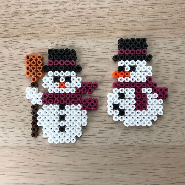 two snowmen made out of legos sitting on top of a wooden table