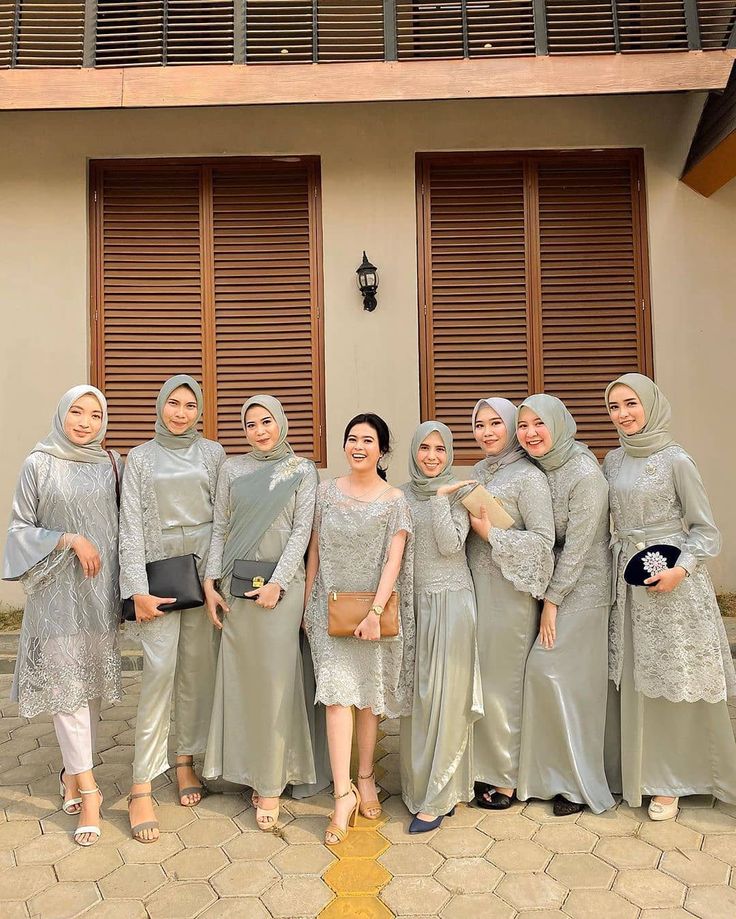 a group of women standing next to each other in front of a building with shutters