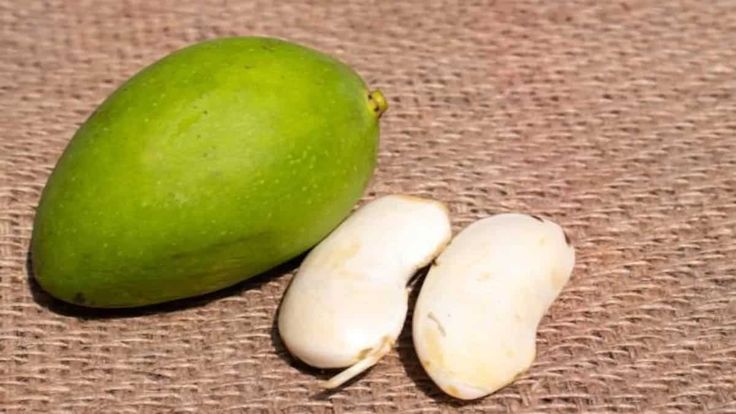 two pieces of green fruit sitting next to each other on a brown cloth covered surface