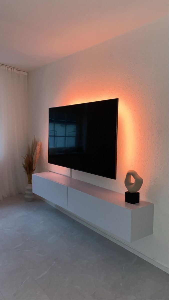 a flat screen tv sitting on top of a white entertainment center next to a window