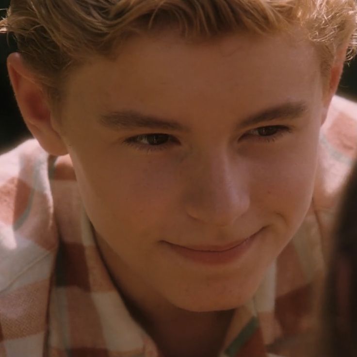 a close up of a person wearing a checkered shirt and looking at the camera