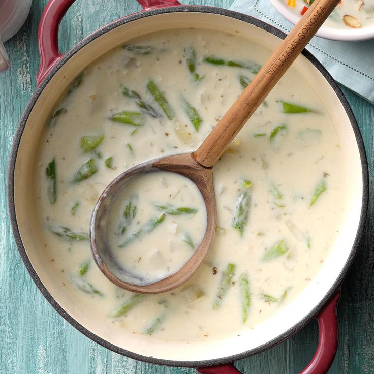 a pot full of soup with a wooden spoon in it and some plates on the side