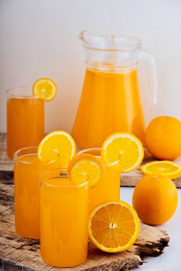 orange juice in glasses next to sliced oranges