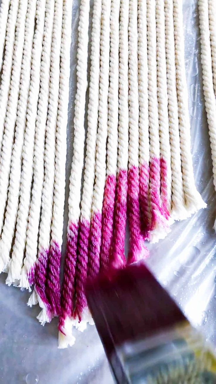 some white and pink pieces of yarn on a table with a purple object next to it